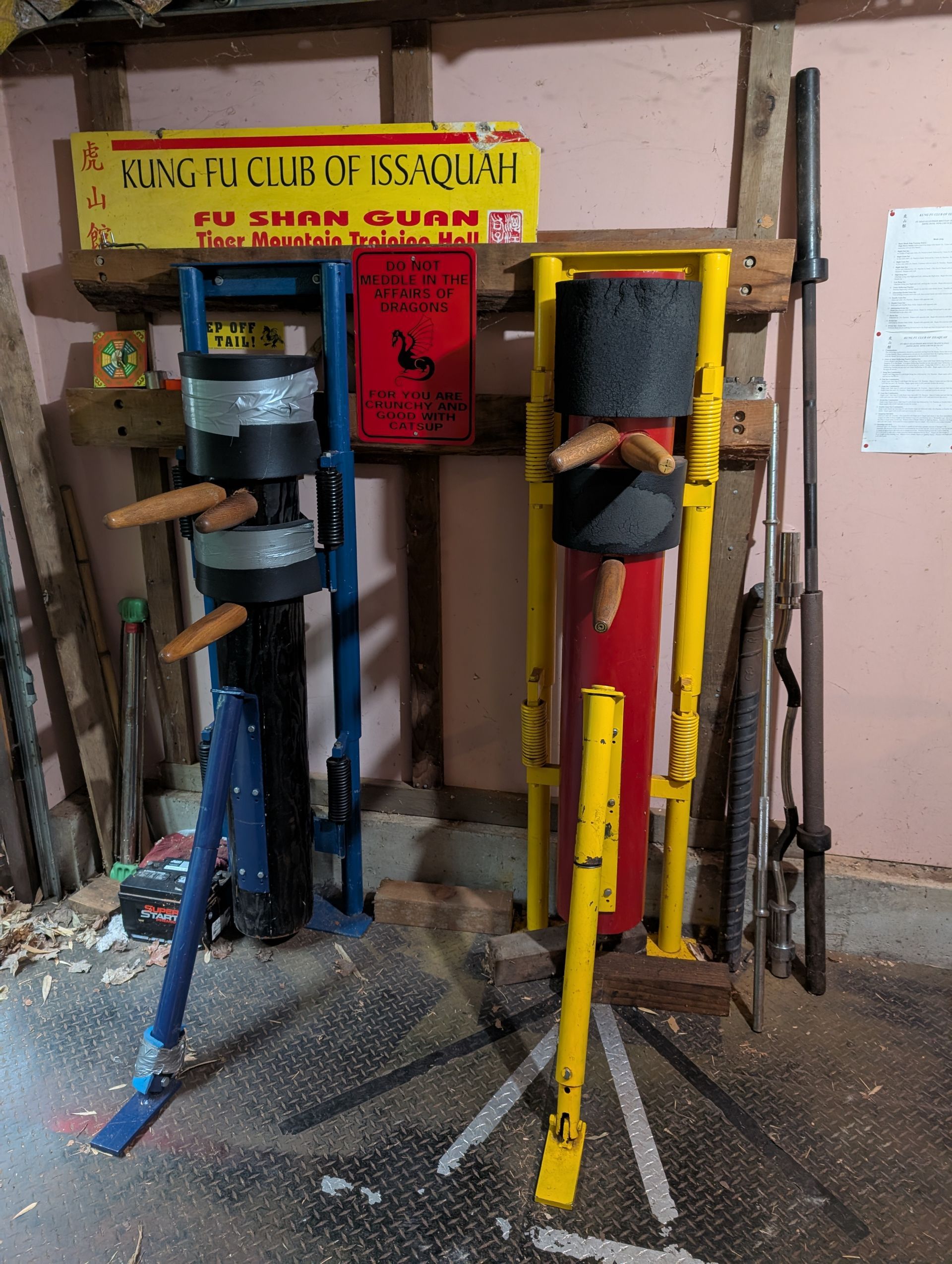 A student standing beside a wooden dummy in the training hall