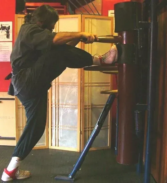 A student practicing on the wooden dummy